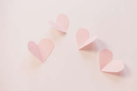 Pink paper hearts on a light pastel background. Concept of romance, love, valentine's day. Minimalism, copy space, paper art.の写真素材