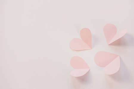 Pink paper hearts on a light pastel background. Concept of romance, love, valentine's day. Minimalism, copy space, paper art.の写真素材