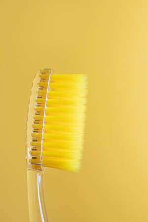 Toothbrush with yellow bristles on a yellow background close-up. Oral hygiene, dentistry, teeth...