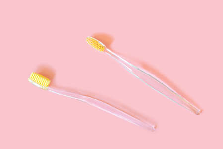 Toothbrushes with yellow bristles on a pink background. Oral hygiene, dentistry, teeth cleaning...