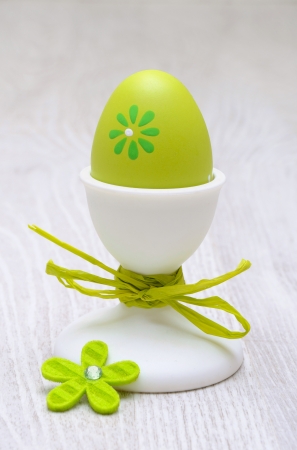 green easter egg in egg-cup on wooden backgroundの写真素材