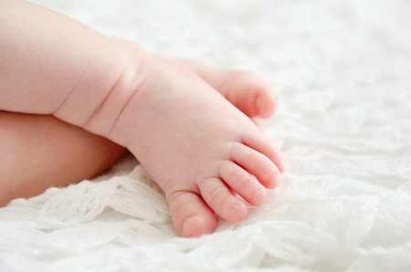 close-up shot of one month old baby's feet toes on white knitted wrap