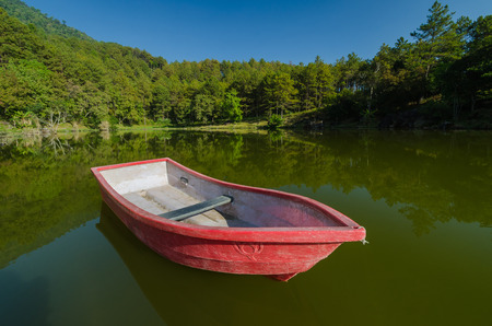 Red boat in lake and reflection with blue skyの写真素材