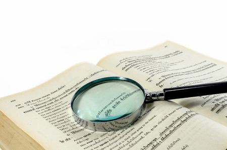 Magnification glass over a opened old book on white background