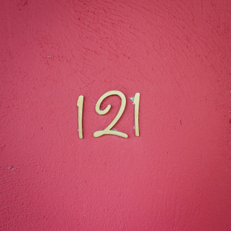Number 121 on red wall texture close upの写真素材
