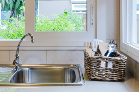 basket of utensil with sink in kitchenの写真素材
