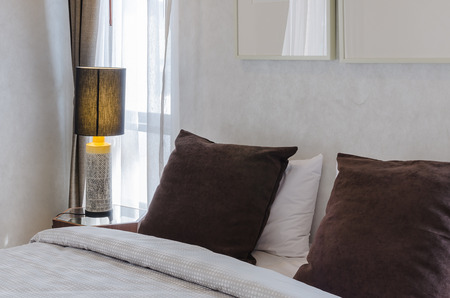 brown pillows on bed with lampの写真素材