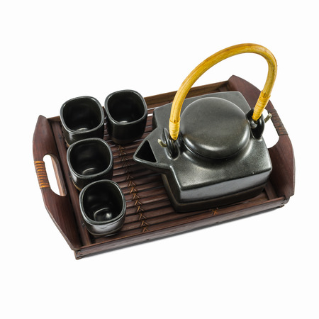 Chinese black teapot and teacups on the wooden trivet isolated on whiteの写真素材