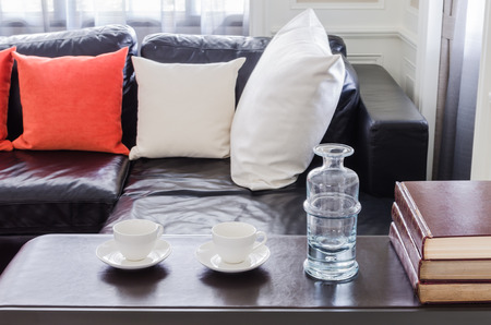 glass of water and white tea cups on wooden table in living roomの写真素材