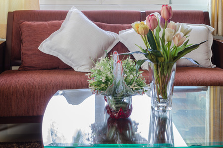 glass vase of flower on glass table with red wooden sofa in living roomの写真素材
