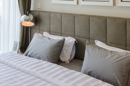 grey pillows on bed with modern lamp at homeの写真素材