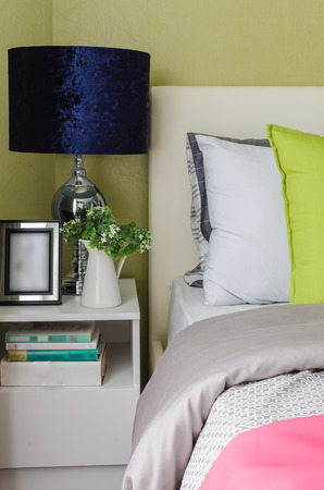 lamp on table side with vase of plant in bedroomの写真素材