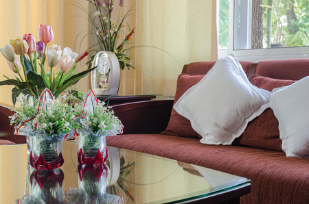 living room with red fabric wooden sofa and flower in glass vaseの写真素材