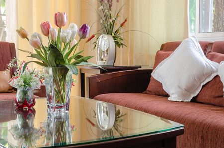living room with red wooden sofa and vase of flower on tableの写真素材
