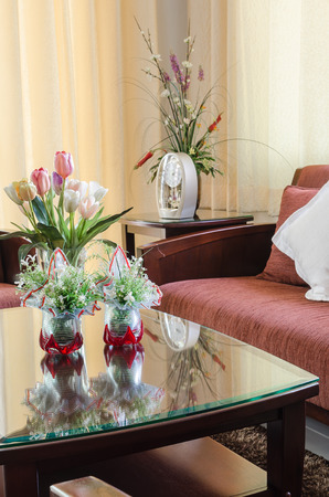 living room with wooden sofa and flower in glass vaseの写真素材