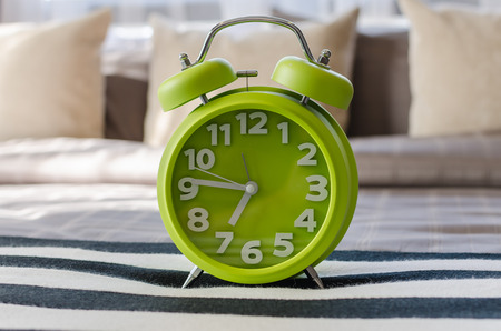 modern green alarm clock on bed at homeの写真素材