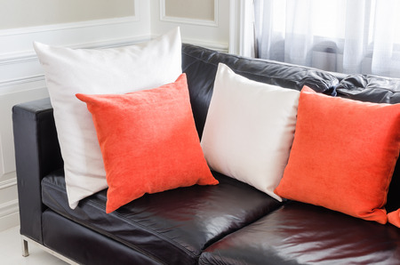 orange and white pillows on modern black sofa in living roomの写真素材