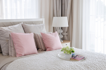 pink pillows on bed with tray of flower at homeの写真素材