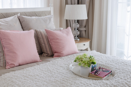 pink pillows on bed with white tray of flower at homeの写真素材