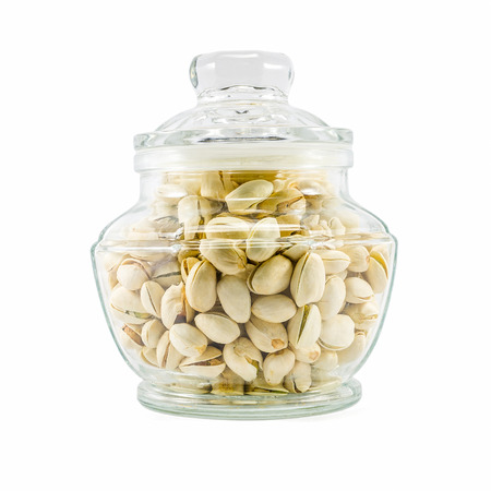 Pistachio nuts in glass bowl isolated on white backgroundの写真素材