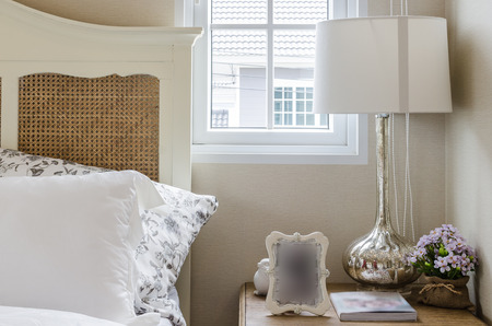 classic lamp style with frame and book on wood table in bedroom
