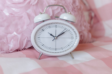 white modern alarm clock on pink bed in bedroomの写真素材