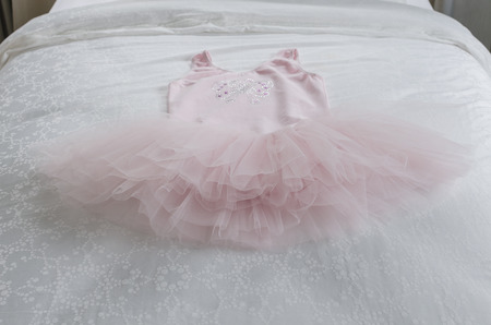 pink girl's dress on bed in bedroom at homeの写真素材