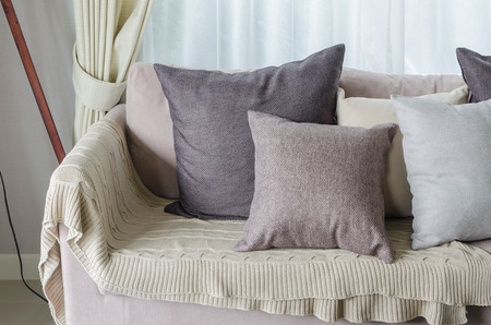 pillows and blanket on earth tone sofa in living roomの写真素材