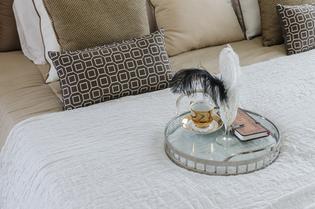 round glass tray of cup and book on bed at home