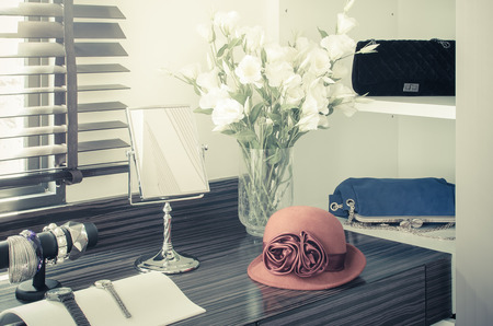 orange female hat on dressing table with vase of flower in vintage styleの写真素材