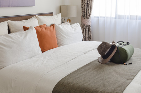 pillows on bed in modern living room with travel hat and bag at homeの写真素材