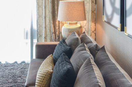 gold and black color pillows on grey sofa in living roomの写真素材