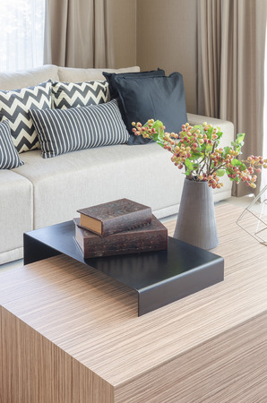 modern wooden table with books and vase of plant in living roomの写真素材