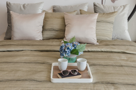 glasses on black book with cup of coffee in wooden tray and vase of flower