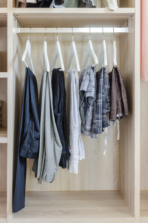 clothes hanging in wooden wardrobe at homeの写真素材
