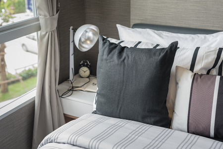 black pillow on modern bed in bedroom with modern white lamp