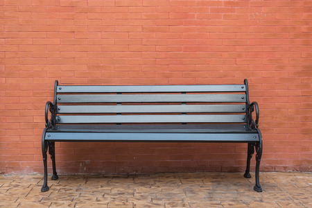black wooden classic bench with brick wall on concrete floor