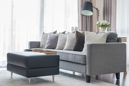 modern grey sofa with pillows and black table in living room at home