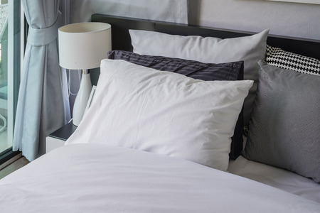 white pillow in modern bedroom with white lamp on table at homeの写真素材