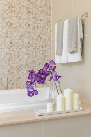 glass vase of flower on bath tub with towel hanging on wallの写真素材