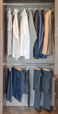 clothes hanging on rail in wooden wardrobe at homeの写真素材