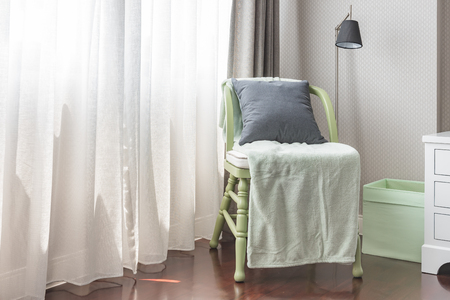 green wooden chair with grey pillow and green blanket in bedroomの写真素材