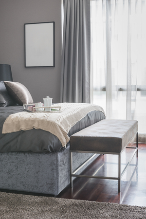 tray of tea cup set on bed in luxury bedroom with bench on wooden floorの写真素材