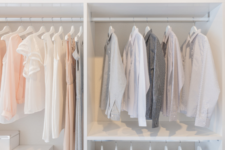 dress and shirts hanging on rail in white wardrobeの写真素材
