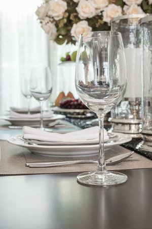empty wine glass on wooden dinning table with table set in dinning roomの写真素材