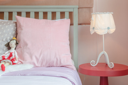 girl's bedroom in pink color tone with doll on bed at homeの写真素材