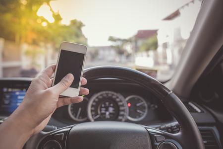 driver using white touch screen smartphone in car - vintage picture styleの写真素材