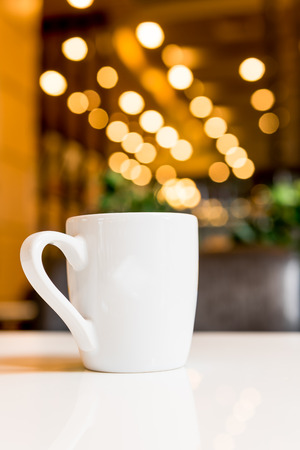 white coffee cup in coffee shop with bokeh light effectの写真素材