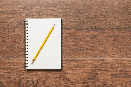 yellow pencil with blank note book on wooden background, top viewの写真素材