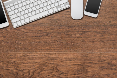 Office wooden table with tablet, keyboard, mouse and smartphone, top viewの写真素材